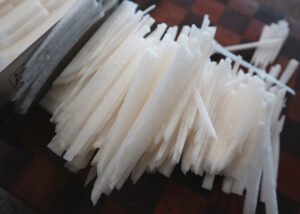 앤드그레인 도마에 무를 생으로 얇게 채썰고 있는 모습